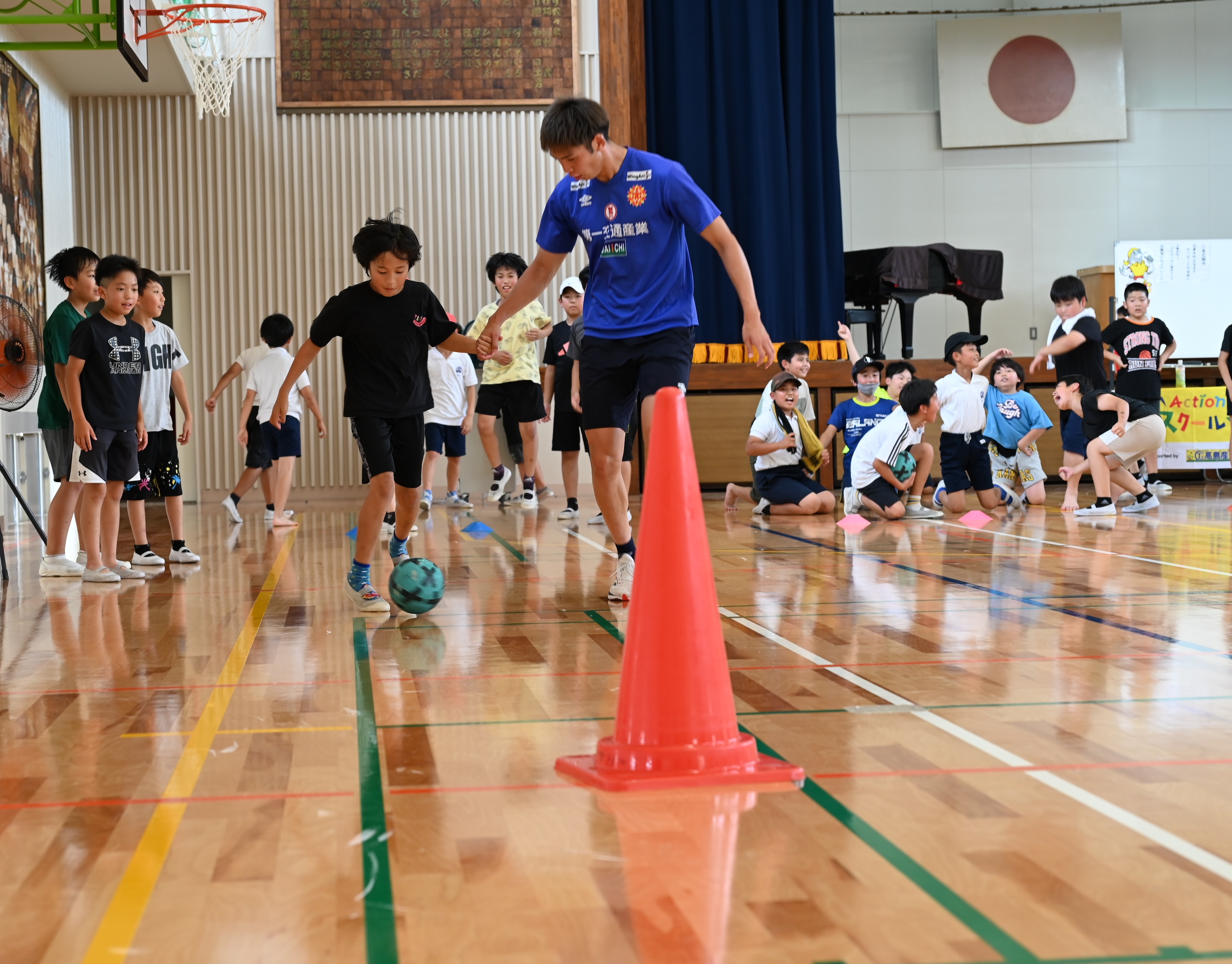 東選手と児童が手をつないでリレーをしている画像
