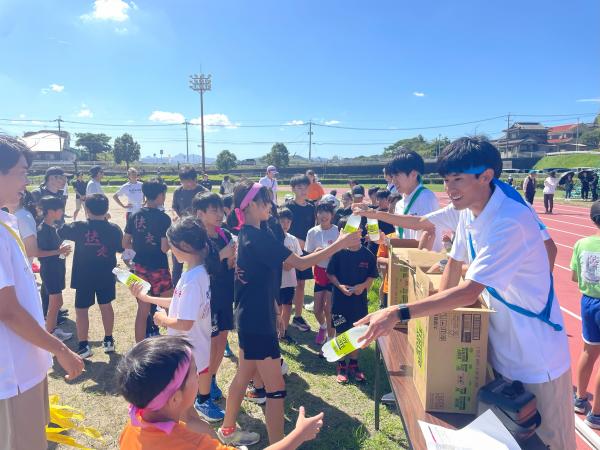 安川電機陸上部の皆さんから缶バッチとドリンクを手渡し